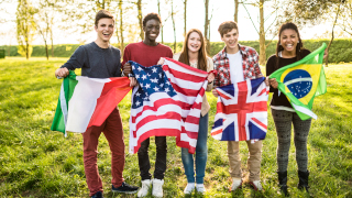 Young people smiling and holding flags of different countries. 