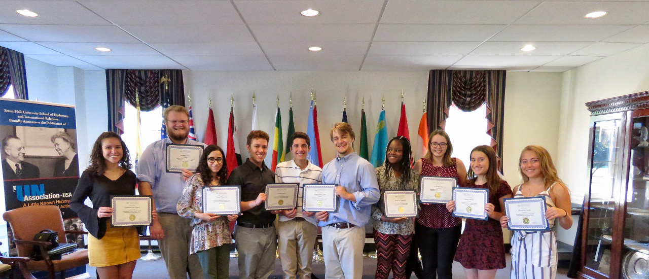 Students from the International Relations Summer Institute holding up their certificates in the Diplomacy room. 