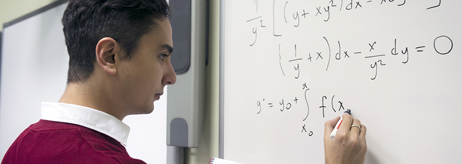 A student working on math problems on a whiteboard.