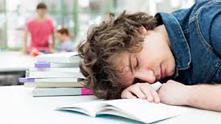 A student sleeps while completing homework.